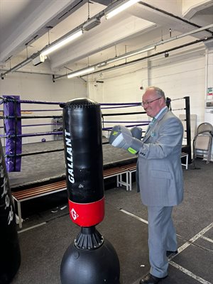 Commissioner with boxing gloves on by a punch bag