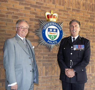 Rupert with Chief Constable Rob Nixon by Force Crest on wall